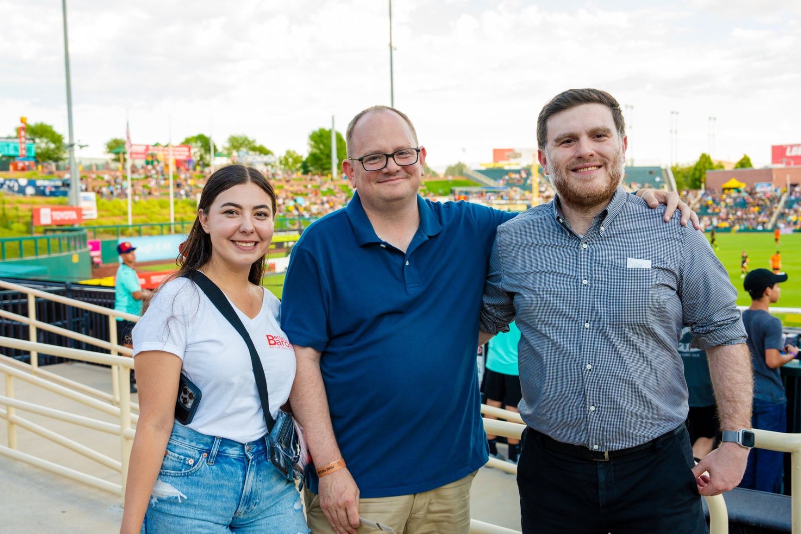 Three Better with Baron clients smiling together in the stands at a New Mexico United soccer game in Albuquerque.