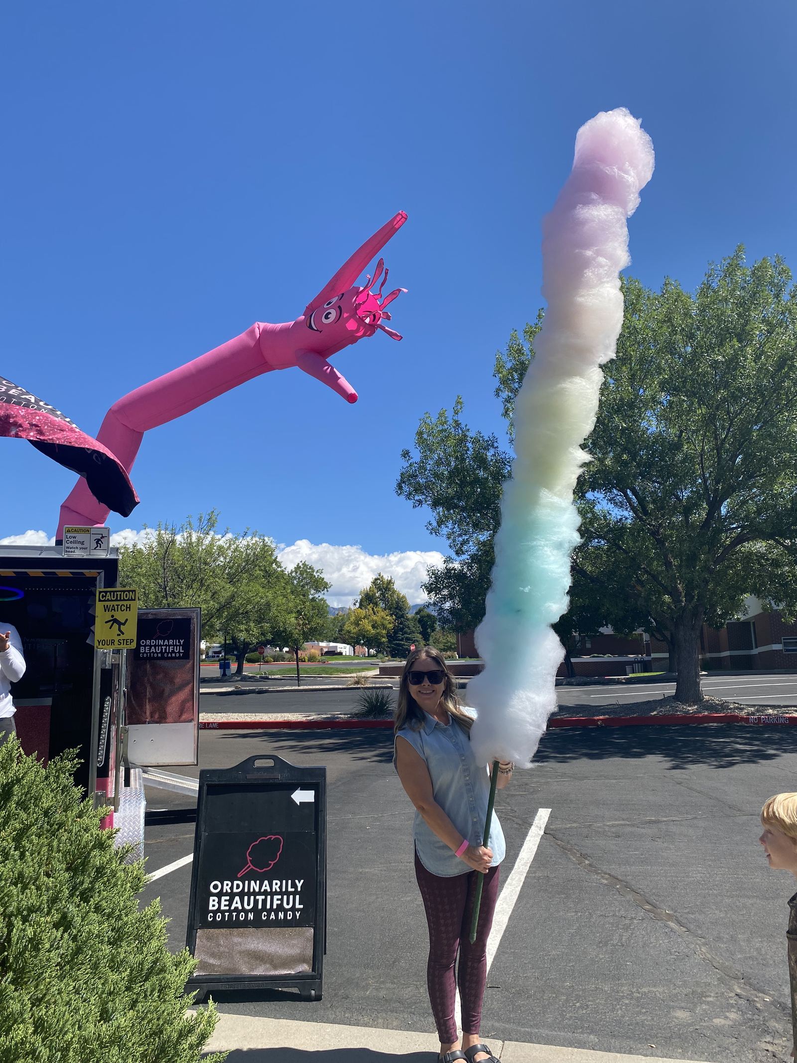 Guest holding an oversized rainbow cotton candy at a Better with Baron community event in Albuquerque, New Mexico