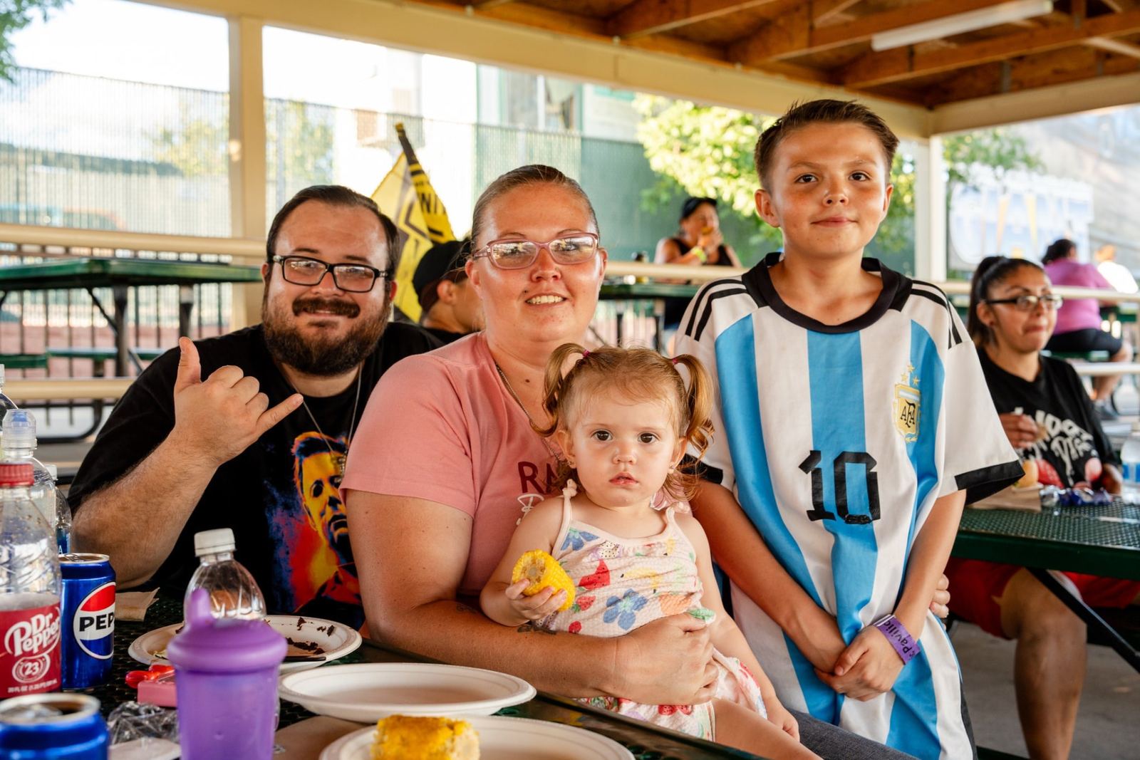 A New Mexico family enjoying dinner in the picnic pavilion at a Better with Baron client appreciation event in Albuquerque.