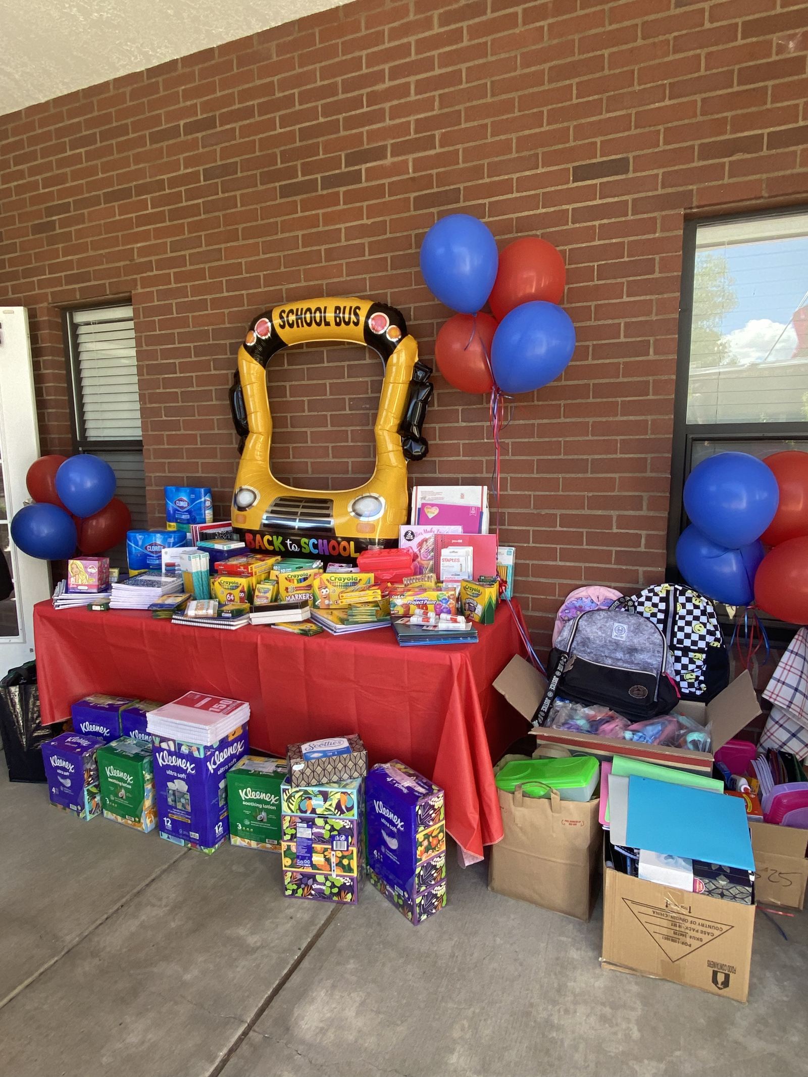 Back-to-school supply drive table stacked with notebooks, crayons and backpacks donated by Better with Baron in Albuquerque