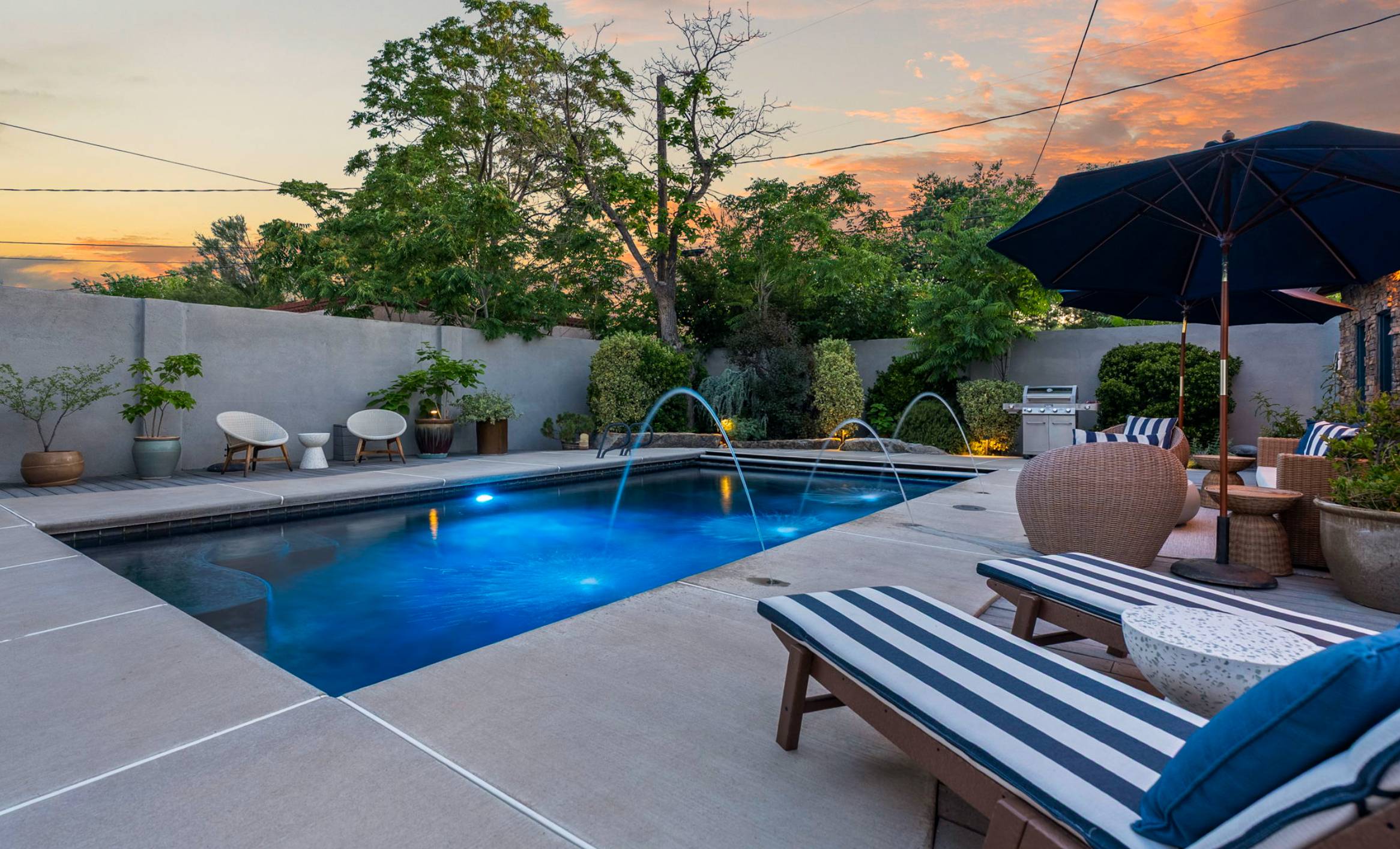 A beautiful backyard in Nob Hill with a pool at twilight. Staged with modern pool furniture. Pool Add Value to Albuquerque Homes
