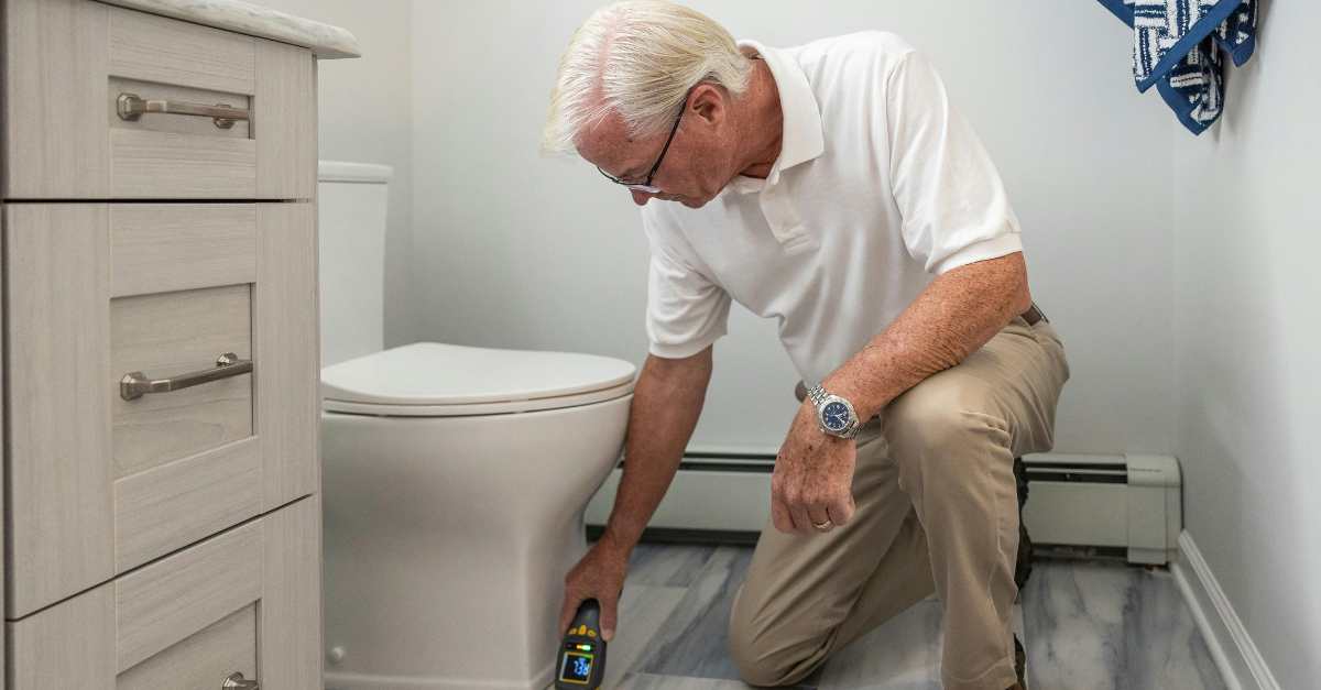 An older man inspecting a bathroom in a home.